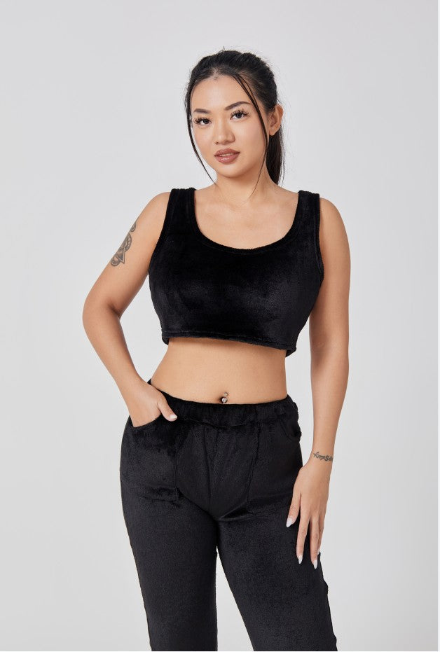 Woman wearing a black sleeveless top and black pants on a light gray background
